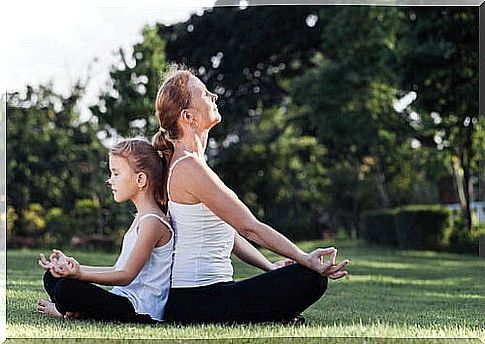 Mother and daughter meditating outdoors