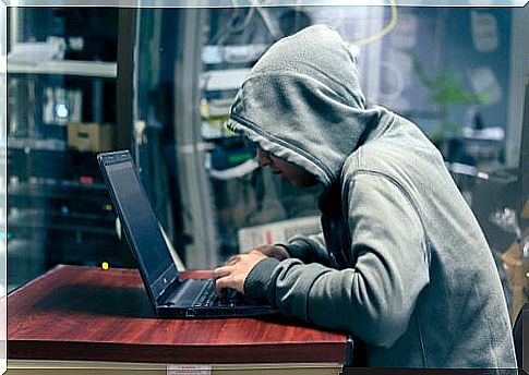 Man with a hood in front of a computer