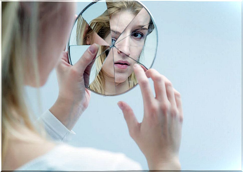 Woman looking in broken mirror