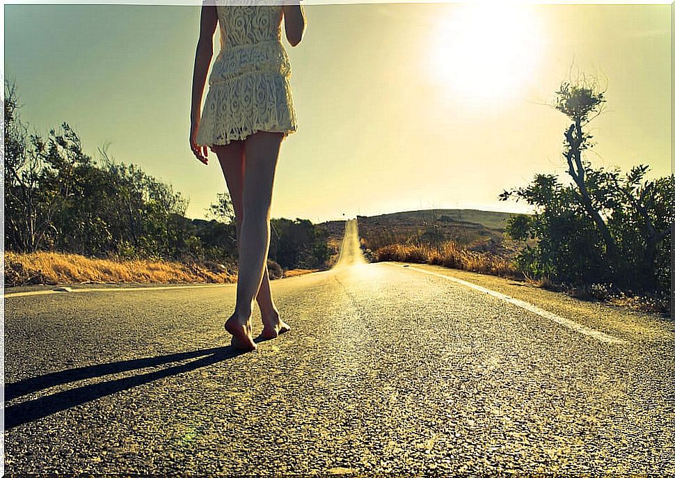 Woman walking barefoot on the road